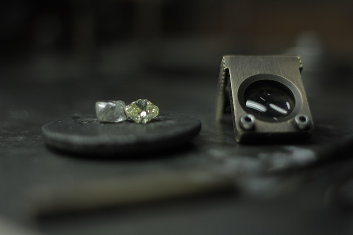A rough diamond next to a polished diamond